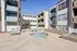 Charming apartment complex with a serene courtyard featuring a bubbling hot tub and comfortable lounge chairs under clear blue skies.