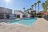 Gorgeous apartment community featuring a refreshing pool surrounded by palm trees and modern architecture, perfect for relaxation and leisure.