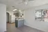 Bright and airy apartment kitchen featuring sleek grey cabinets, modern white appliances, and a cozy breakfast bar.