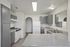 Modern kitchen with sleek gray cabinets, dual sink, and spacious countertop featuring an arched entryway and bright lighting.