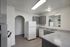 Modern kitchen with sleek gray cabinetry, spacious countertops, and stainless steel appliances, featuring an inviting arched doorway.