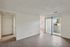 Bright entrance of a modern apartment with sleek flooring and sliding glass doors leading to a sunlit balcony.