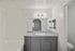Bright bathroom with sleek vanity, large mirror, and white tiled bathtub, offering modern and clean aesthetics.