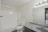 Modern bathroom featuring sleek white tile bathtub, elegant vanity, and bright lighting fixtures.