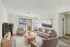 Bright and elegant living room with modern furniture, sleek wooden flooring, and natural light streaming through large sliding doors.