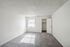 Bright and airy bedroom with plush gray carpeting, large window providing natural light, and a spacious closet in a modern apartment.