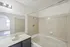 Bright and inviting bathroom featuring a sleek bathtub, elegant tile design, and a stylish vanity with a large mirror.