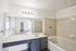 Bright and inviting bathroom with a modern vanity, spacious bathtub, and elegant mirror design, perfect for relaxation and rejuvenation.