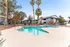 Inviting outdoor pool surrounded by palm trees and modern apartment buildings, offering a serene living experience.