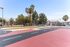 Vibrant outdoor sports court with colorful markings, surrounded by lush palm trees, creating a lively community space.