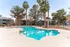 Inviting outdoor pool area surrounded by lush palm trees, offering a relaxing oasis in a vibrant residential community.