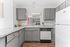 Modern kitchen with sleek gray cabinets, granite countertops, and stylish appliances. Bright, open space accented with fresh orange decor.