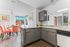 Bright kitchen and dining area with modern gray cabinets, vibrant coral chairs, and artistic decor, creating a welcoming and stylish atmosphere.