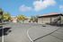Beautiful basketball court under a clear blue sky, surrounded by lush greenery and houses with red-tiled roofs.