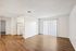 Bright, open-plan apartment interior with sleek hardwood flooring and natural light filtering through vertical blinds.