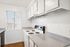 Bright and modern kitchen with sleek white cabinetry, granite countertops, and efficient appliances illuminated by natural light.