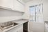 Bright, modern kitchen with sleek countertops, stainless steel sink, and large window with vertical blinds.
