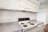 Modern kitchen featuring sleek white cabinetry and a pristine electric stove, offering a clean and inviting space perfect for culinary adventures.