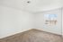 Bright, spacious bedroom with plush carpet and large window, offering natural sunlight and a serene view.