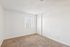 Bright, cozy room with plush carpeting, white walls, and a large window with vertical blinds.