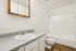 Bright, modern bathroom featuring elegant fixtures, glossy countertop, spacious vanity, and a pristine bathtub with warm wood flooring.