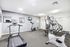 Modern apartment fitness center equipped with treadmill, elliptical, and versatile weight machine, featuring bright lighting and sleek decor.