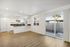 Bright open-concept living space with sleek kitchen, large windows, and sliding glass doors leading to a private patio.