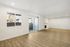 Bright and spacious living room with elegant hardwood floors, sleek white fireplace, and large window offering a serene view.
