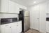 Sleek and modern kitchen with elegant white cabinetry, stainless steel refrigerator, and stylish dark countertops.