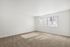 Bright and airy room with soft carpet flooring, featuring large windows letting in ample natural light.