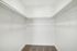 Spacious walk-in closet with ample shelving and hanging space, featuring plush carpet and bright white walls for a sleek, modern look.