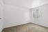 Bright and airy bedroom featuring soft carpet flooring and a large window with vertical blinds, perfect for cozy living.