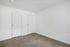 Bright and spacious empty room with plush carpet and two pristine white doors, ideal for customizable living space.