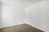 Bright and spacious empty room with soft carpet flooring and a pristine white door, ready to be transformed into your ideal space.