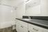 Elegant bathroom with modern white vanity, sleek countertop, and pristine subway tile shower.