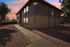 Charming apartment complex exterior with a sunset backdrop, featuring a shaded pathway lined with greenery.