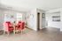 Bright dining area with stylish red chairs, modern decor, and an inviting open layout leading to the kitchen.