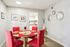 Elegant dining area with red cushioned chairs, a wooden table adorned with vibrant decor, and wall art creating a chic ambiance.