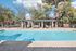 Inviting outdoor pool area with shaded pergola, surrounded by lush trees and comfortable lounge chairs, perfect for relaxation.