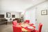 Bright and inviting living-dining area featuring red-accented dining chairs, a cozy sofa set, modern decor, and elegant lighting.