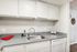 Contemporary kitchen with sleek gray countertops, stainless steel sink, and white cabinetry, featuring a modern dishwasher and charming 'Coffee Time' sign for a cozy atmosphere.