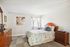 Inviting bedroom featuring a plush floral bed, elegant wooden furniture, and soft natural light streaming in.