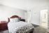 Inviting bedroom with elegant wooden furniture, chic floral bedding, and soft carpet flooring leading to a bright en-suite bathroom.