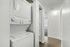 Bright hallway featuring a modern in-unit washer and dryer, leading to a sunlit room with sleek hardwood flooring.
