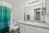 Bright modern bathroom featuring a sleek countertop, spacious mirror, and vibrant teal shower curtain.