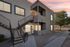 Charming apartment exterior with modern gray facade, stylish balcony, and inviting staircase, set against a picturesque sunset sky.