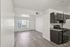Modern apartment interior with sleek laminate flooring, bright open space, and elegant dark kitchen cabinets.
