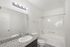 Modern bathroom featuring a sleek granite countertop, large mirror, and a pristine bathtub with contemporary fixtures.