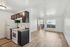 Bright, open-concept apartment with a modern kitchen, featuring sleek black cabinets and white appliances, opening to a sunlit living room with stylish wood flooring.