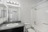Modern bathroom with sleek design featuring a granite countertop, elegant mirror lighting, and pristine bathtub and sink.